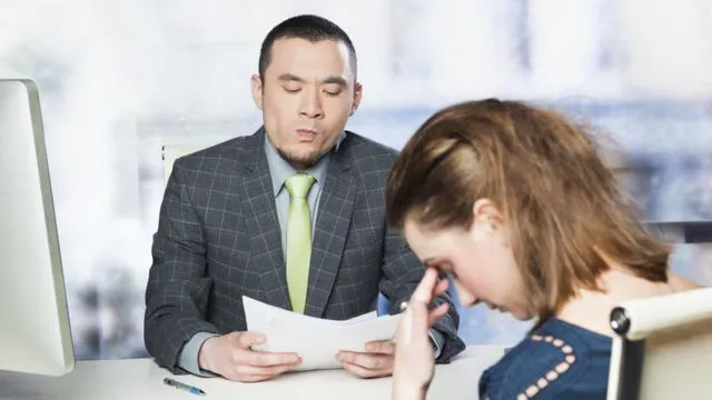 Man reviewing a document; woman with head in hands